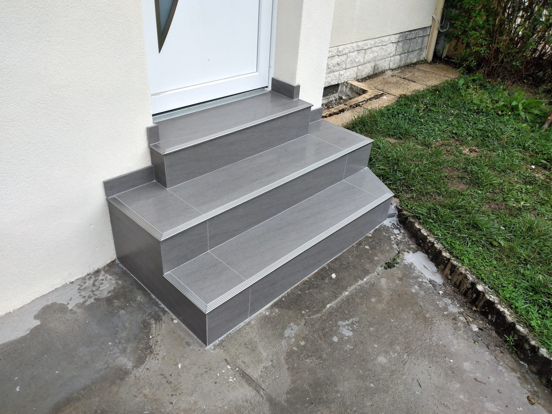 Perron d'entrée carrelé gris avec nez de marche