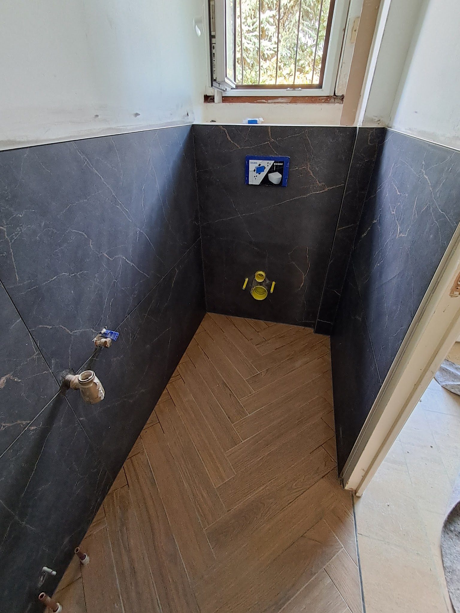 Toilettes : sol en bâtons rompus, murs façon marbre noir